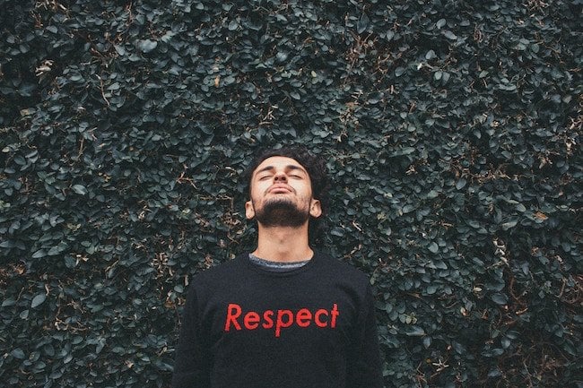 man standing with his head up to the sky, wearing a shirt that says 'respect'; fairness in the workplace is important
