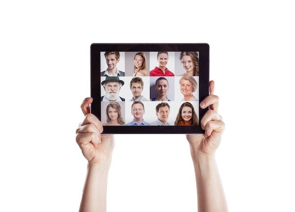 Two hands holding up a tablet where people are video conferencing, which is part of an innovative remote work design